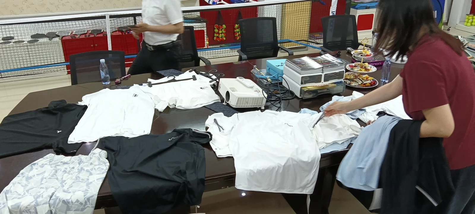 Apparel sample review meeting with tees, shorts, and colorway options on a conference table