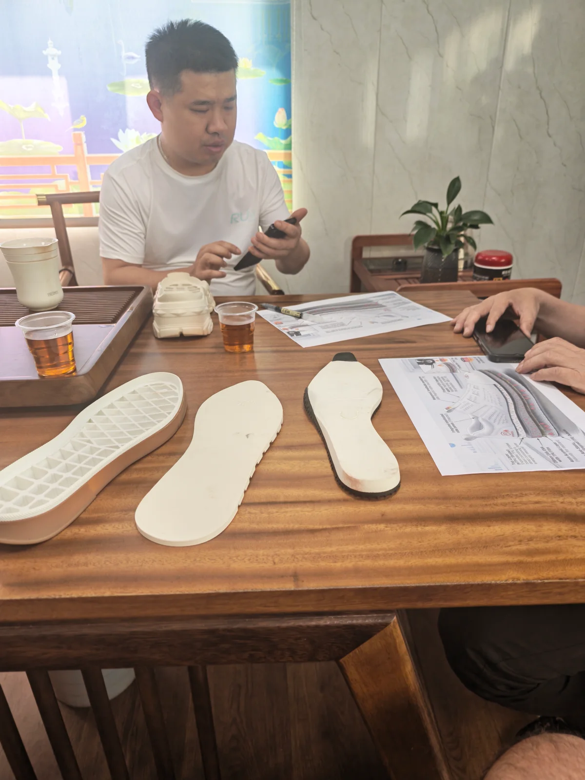 Footwear development meeting reviewing sole components, insoles, and technical drawings